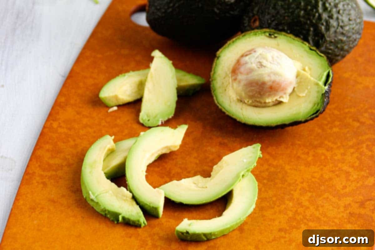freshly sliced avocado on a wooden cutting board, ready for pizza topping
