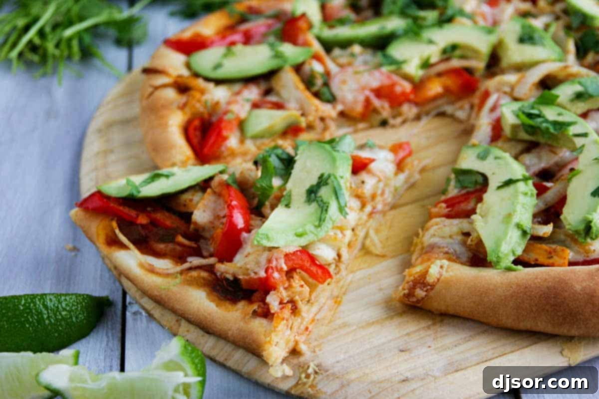 A perfectly baked slice of Turkey Fajita Pizza on a pizza peel, garnished with fresh avocado and cilantro