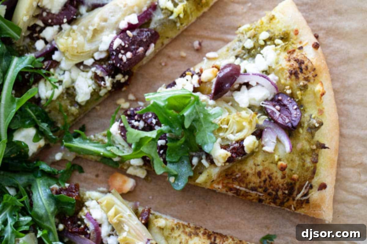 Mediterranean Pizza: A Vibrant Slice of the Coast A delectable slice of Mediterranean Pizza, rich with feta, sun-dried tomatoes, and olives, lifted from the whole pizza.