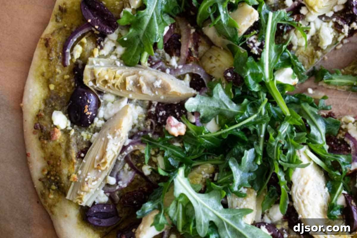 Mediterranean Pizza: A Feast for the Eyes and Palate A vibrant Mediterranean Pizza, sliced and ready to serve, generously topped with fresh arugula, highlighting the colorful array of ingredients.