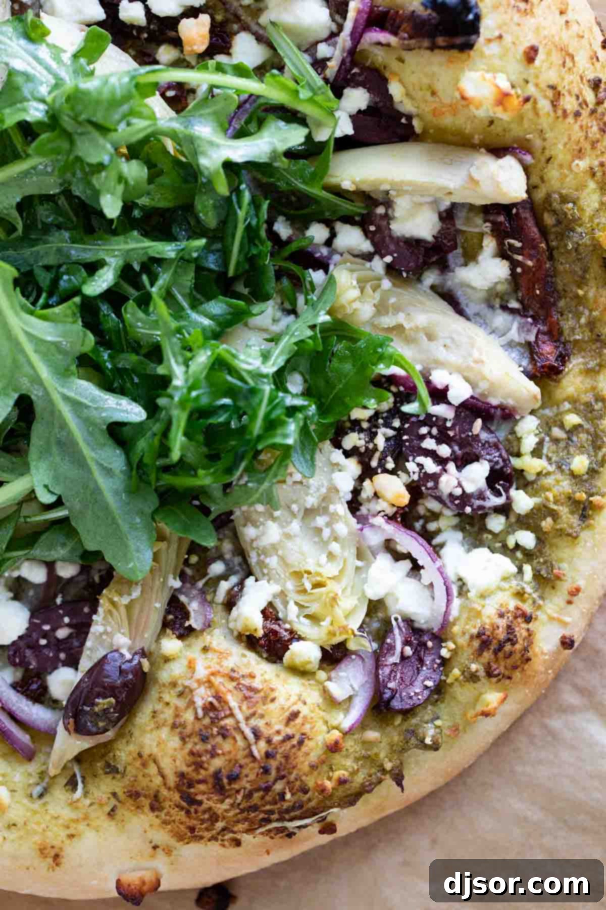 Close-up: The Irresistible Texture of Mediterranean Pizza A mouthwatering close-up of a slice of Mediterranean Pizza, showcasing the rich textures of artichoke hearts, Kalamata olives, and fresh arugula, inviting you to take a bite.