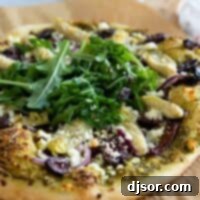 Vibrant Mediterranean Pizza 2 Mediterranean Pizza on parchment paper topped with arugula.