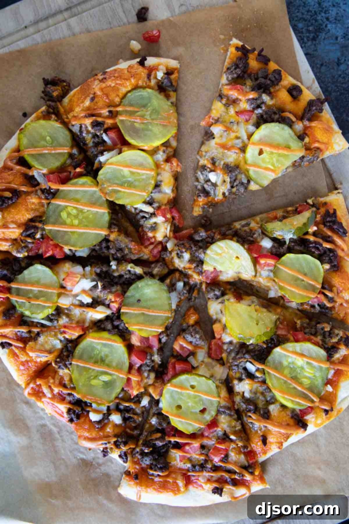 A freshly baked cheeseburger pizza, golden and bubbly, with a final drizzle of special burger sauce on top.