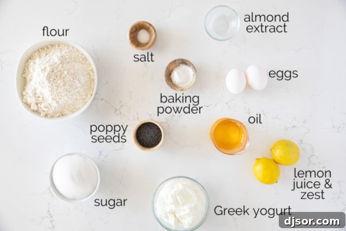 A top-down view of all the fresh ingredients laid out to make Lemon Poppy Seed Muffins: Greek yogurt, sugar, oil, eggs, lemons, almond extract, flour, baking powder, salt, and poppy seeds.