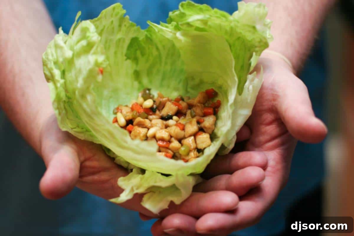 Chicken Soong filling inside of lettuce leaves being held by two hands.