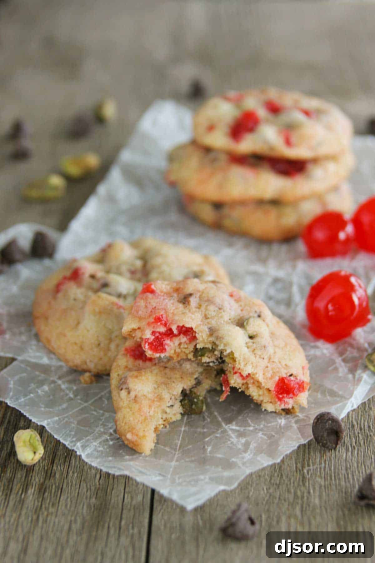 Cherry Chocolate Nut Cookie broken in half, sitting on another cookie, showcasing its soft interior and generous fillings.