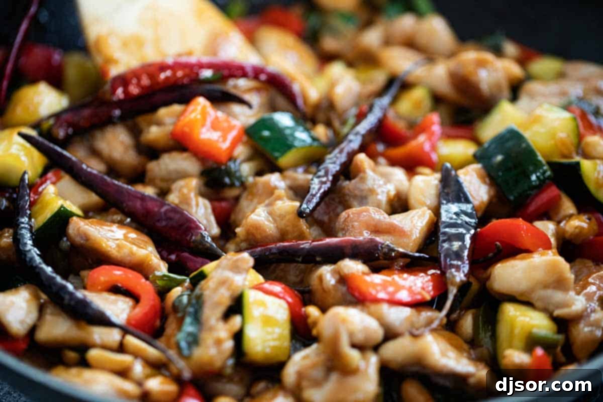 A pan full of freshly cooked, aromatic Kung Pao Chicken, garnished with green onions and peanuts.