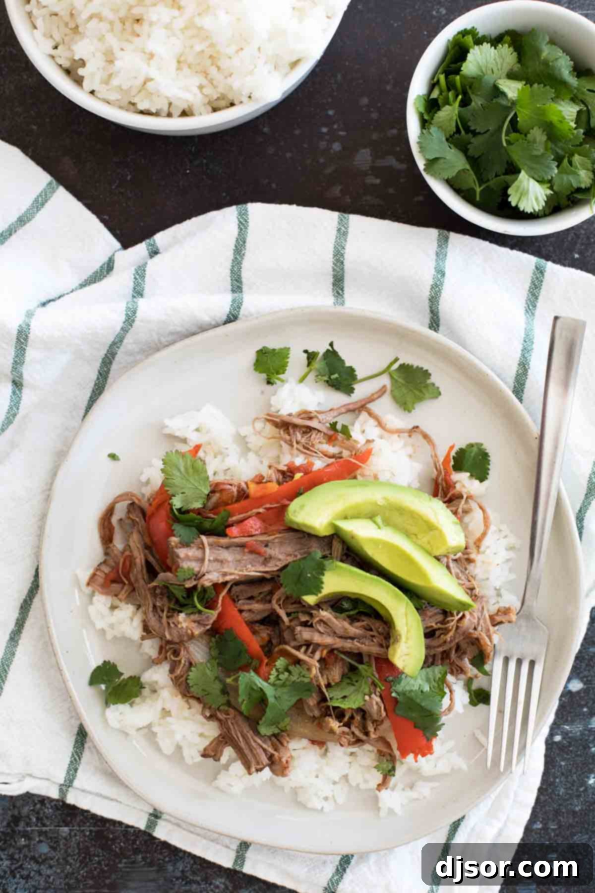 Fall-Apart Slow Cooker Cuban Ropa Vieja 4 A serving of Slow Cooker Cuban Ropa Vieja with rice, ready to be enjoyed.