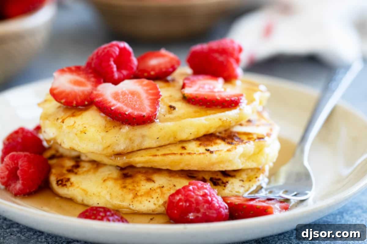 Cottage Cheese Pancakes with fresh strawberries and raspberries, drizzled with syrup.