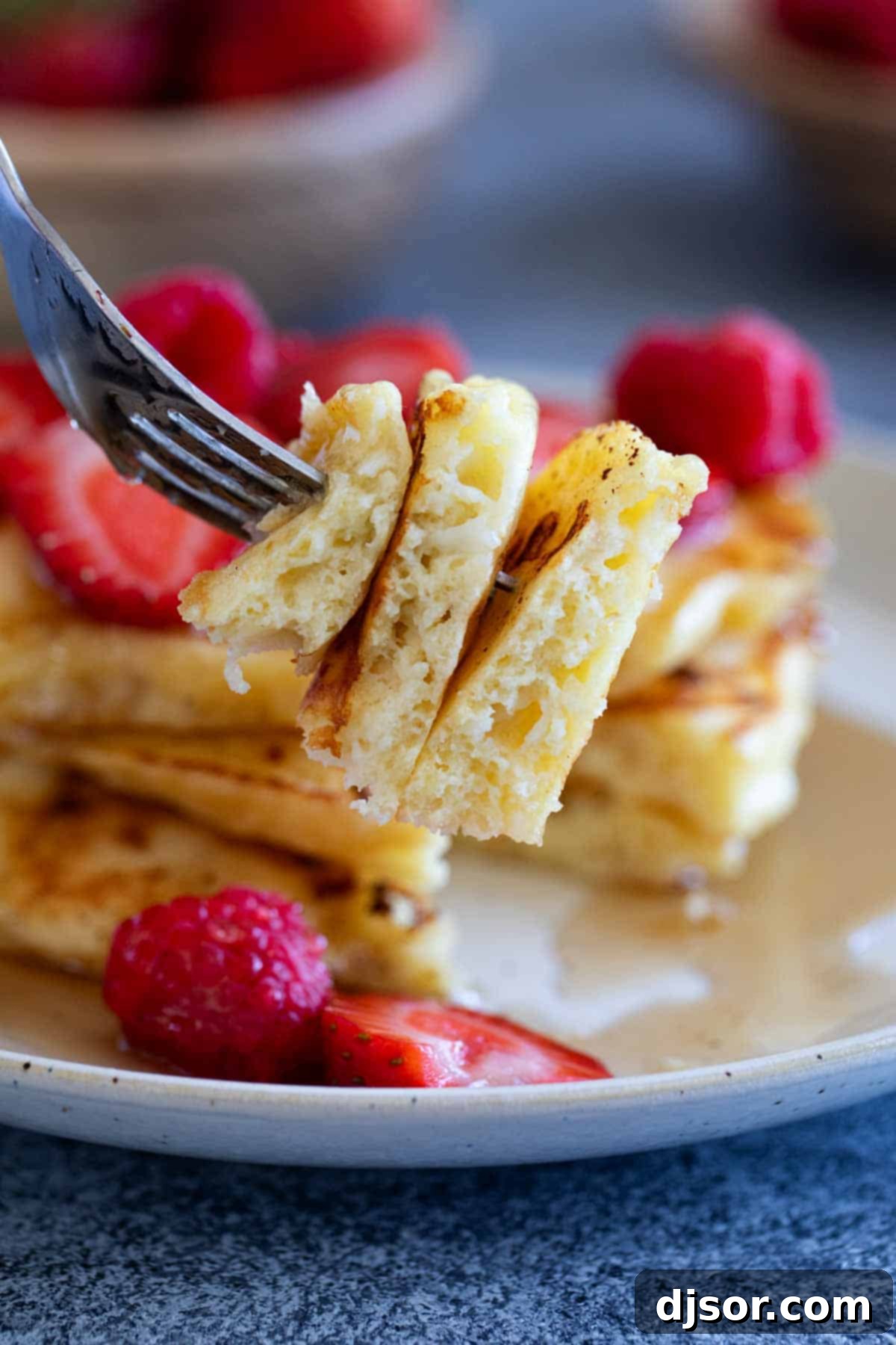 A fork holding a bite-sized piece of cottage cheese pancake, showing the creamy interior.