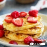 Stack of cottage cheese pancakes topped with syrup and berries.
