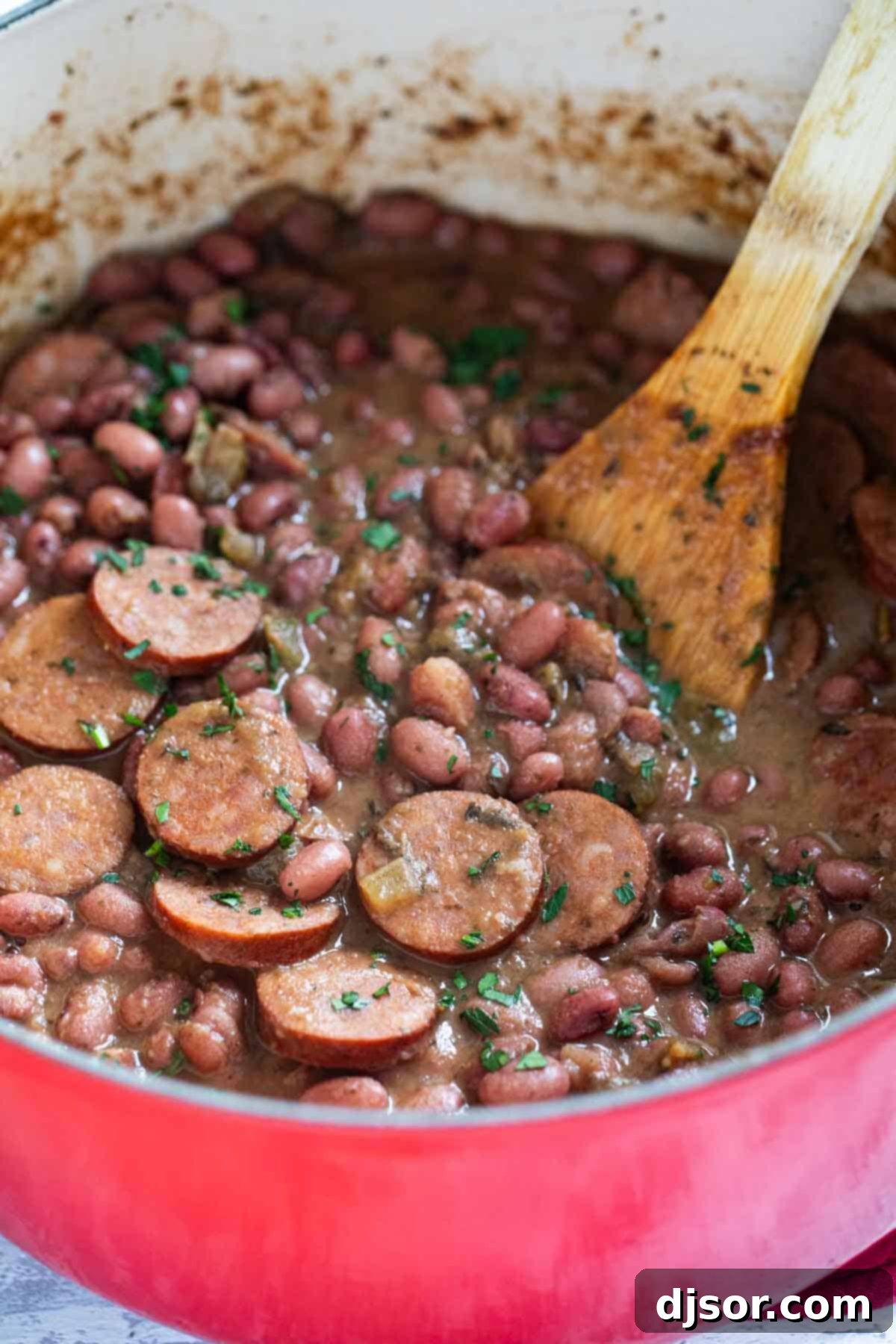 Andouille Red Beans and Rice 5 A Dutch oven filled with creamy Red Beans and Rice and sliced Andouille Sausage, ready to be served.