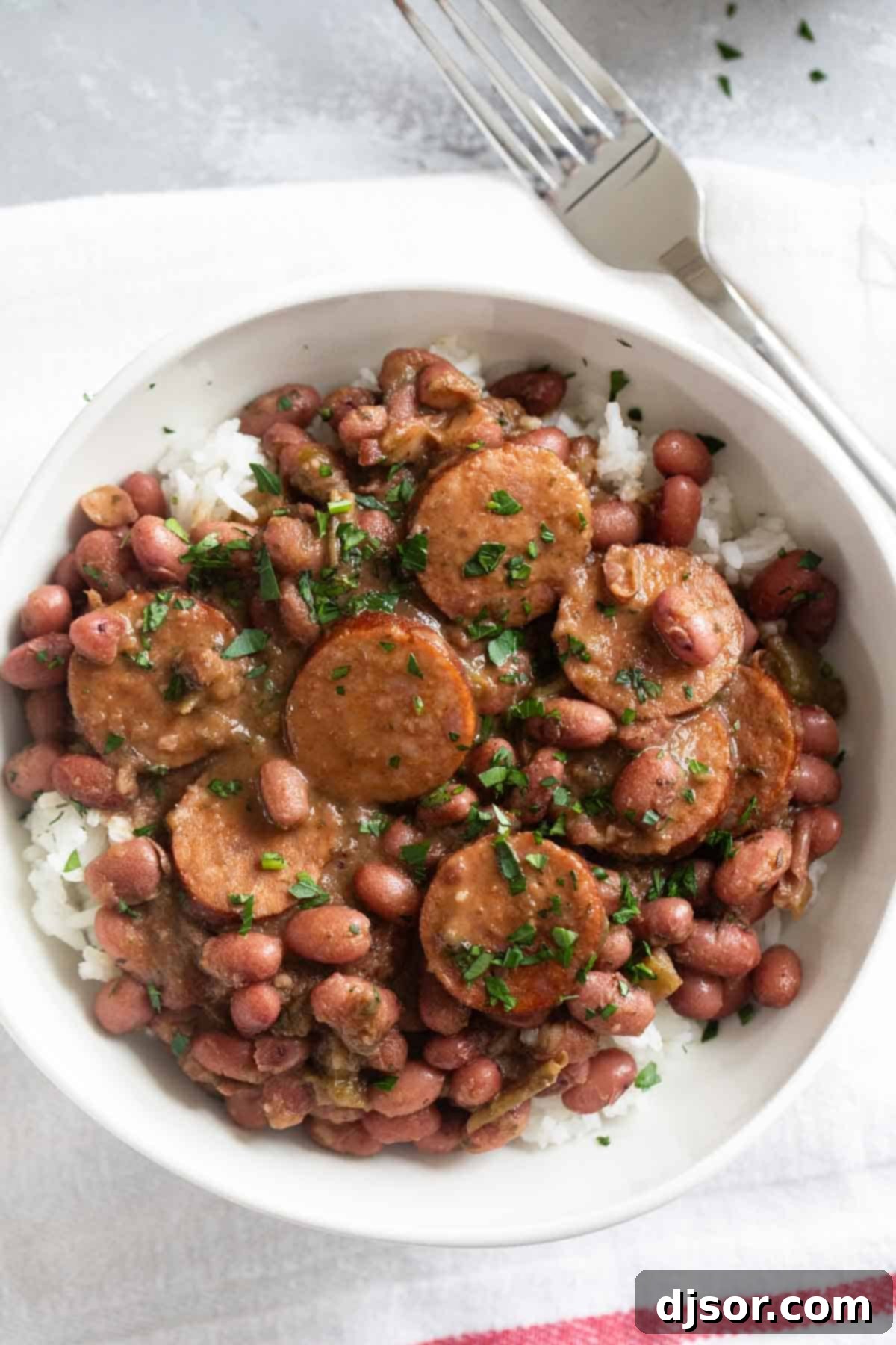 Andouille Red Beans and Rice 6 A beautifully presented bowl of creamy Red Beans and Rice topped with savory Andouille Sausage, ready to be enjoyed.