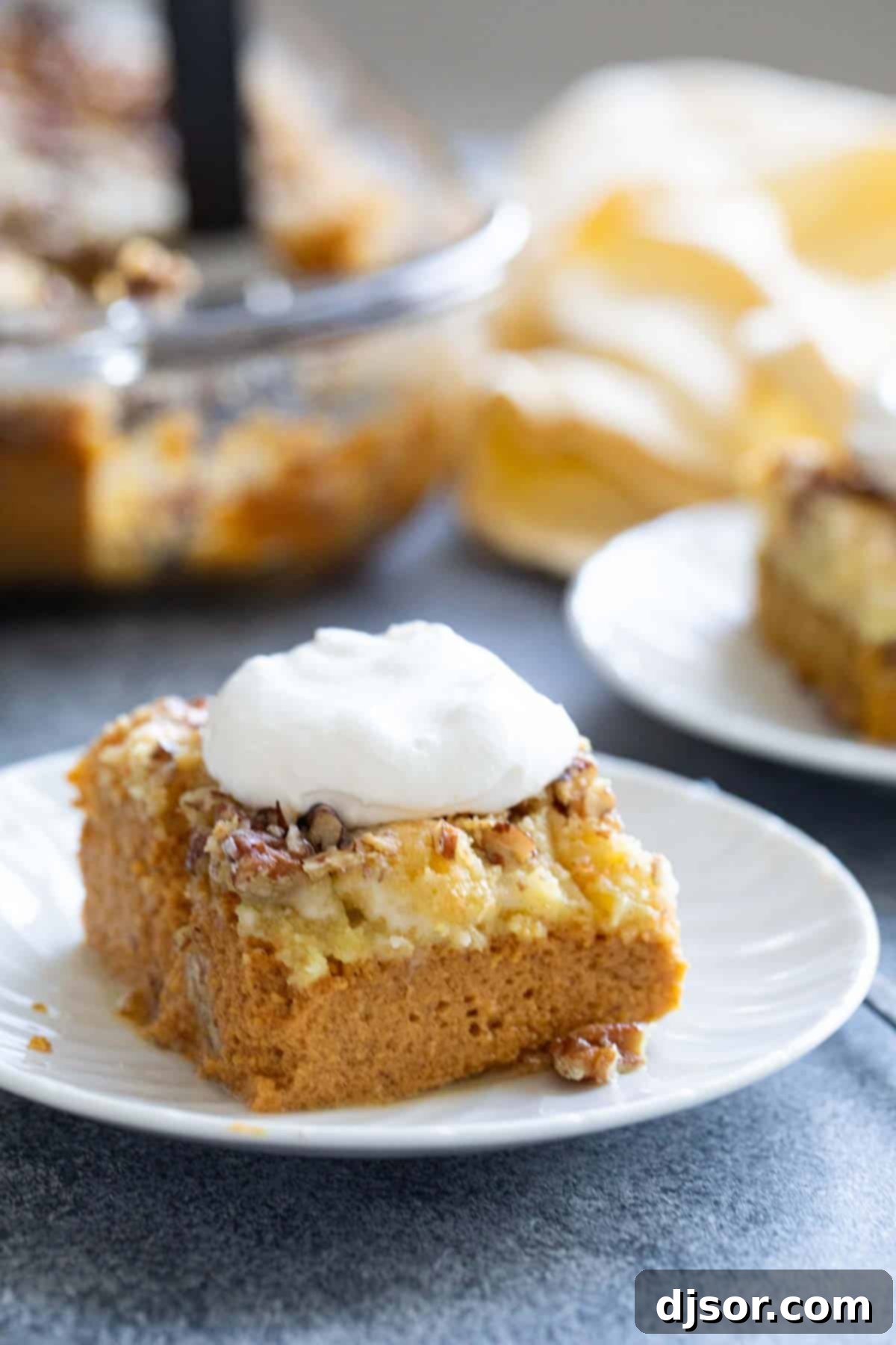 Autumn's Golden Pumpkin Dream 8 A close-up of a delectable slice of pumpkin dump cake, generously topped with pecans and a swirl of fresh whipped cream, ready to be enjoyed.