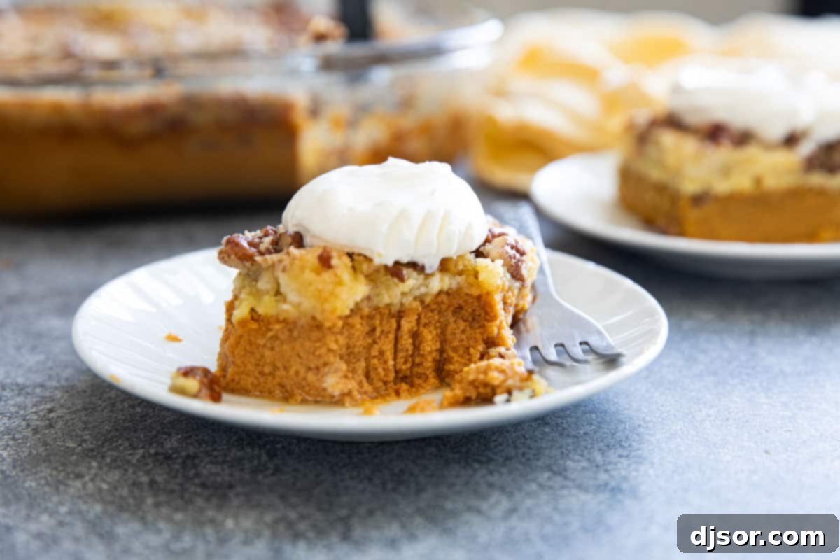 Autumn's Golden Pumpkin Dream 9 A close-up shot of a slice of pumpkin dump cake on a white plate, with a bite taken out, revealing the creamy pumpkin layer and the crumbly cake topping.