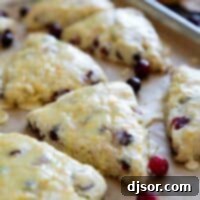 Cranberry orange scones with orange glaze on a baking sheet.