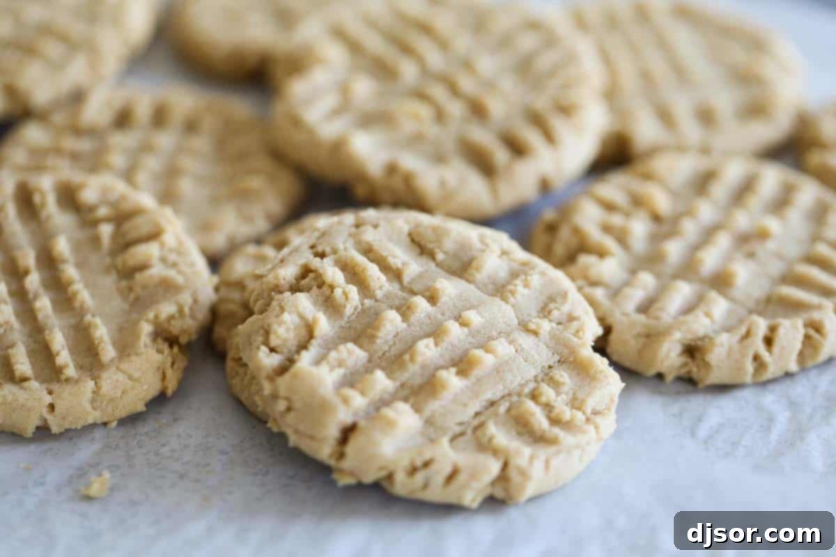 A stack of golden brown, soft and chewy peanut butter cookies on parchment paper, ready to be enjoyed as a classic dessert or after-school snack.