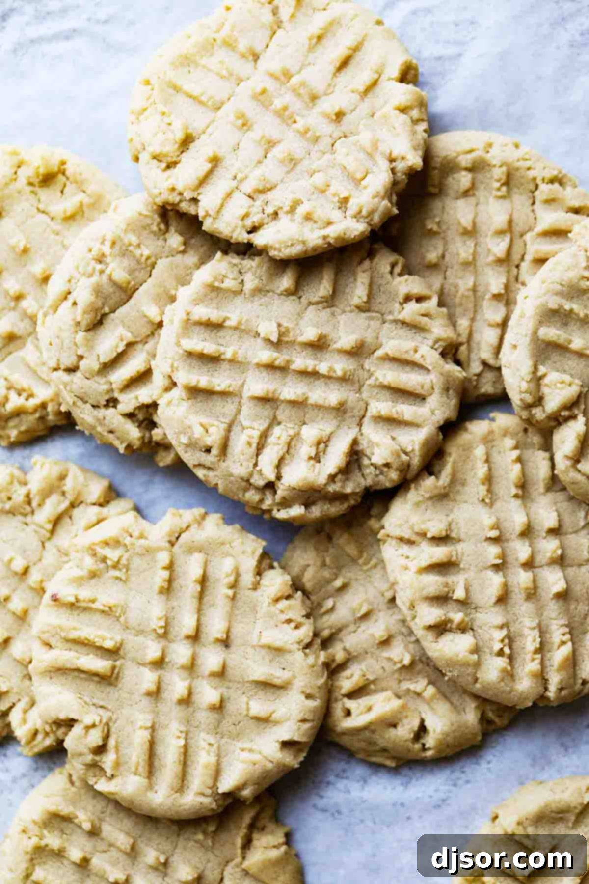 An overhead view of a beautifully arranged stack of golden brown, soft and chewy peanut butter cookies, showcasing their inviting texture and classic criss-cross pattern.
