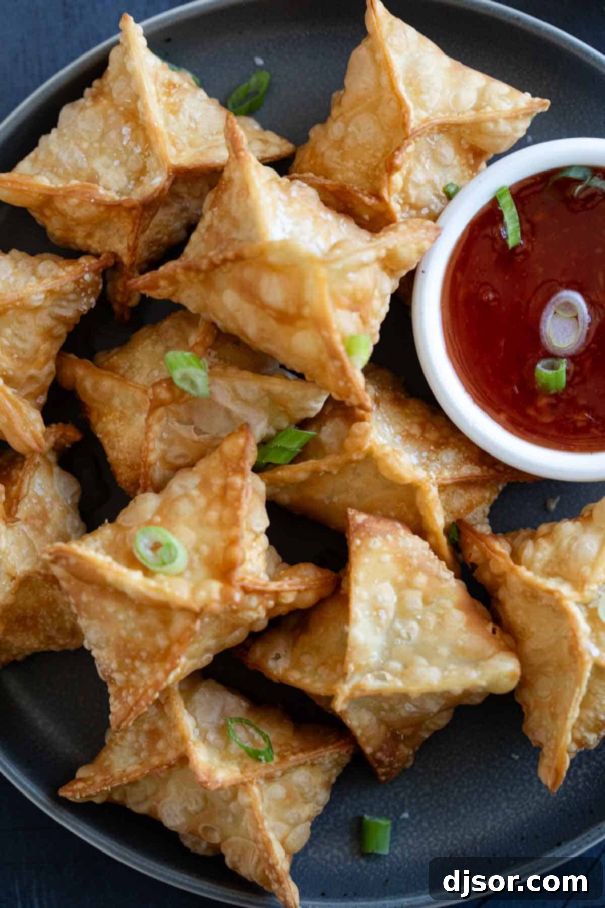 Plate filled with crab rangoon with a bowl of sweet chili sauce.
