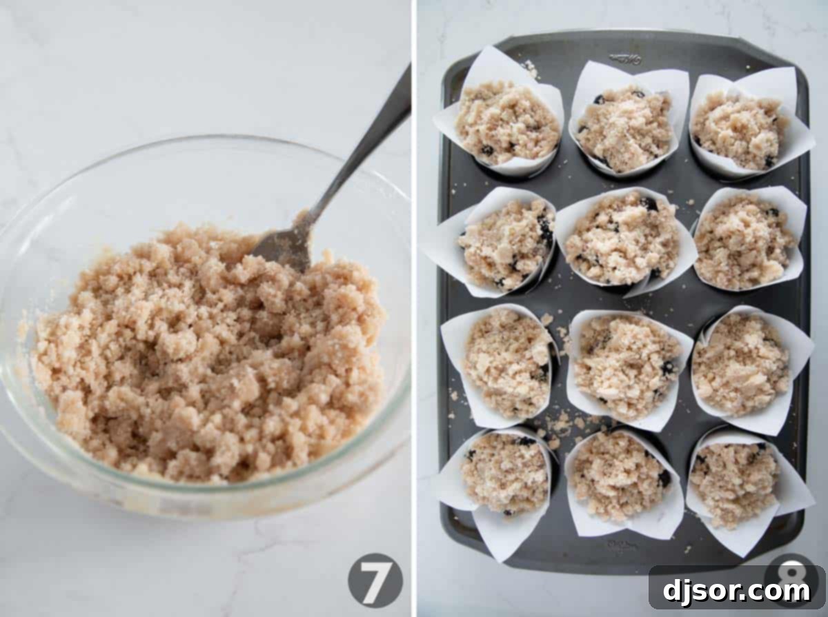 Adding a generous amount of crumb topping to unbaked blueberry muffins.