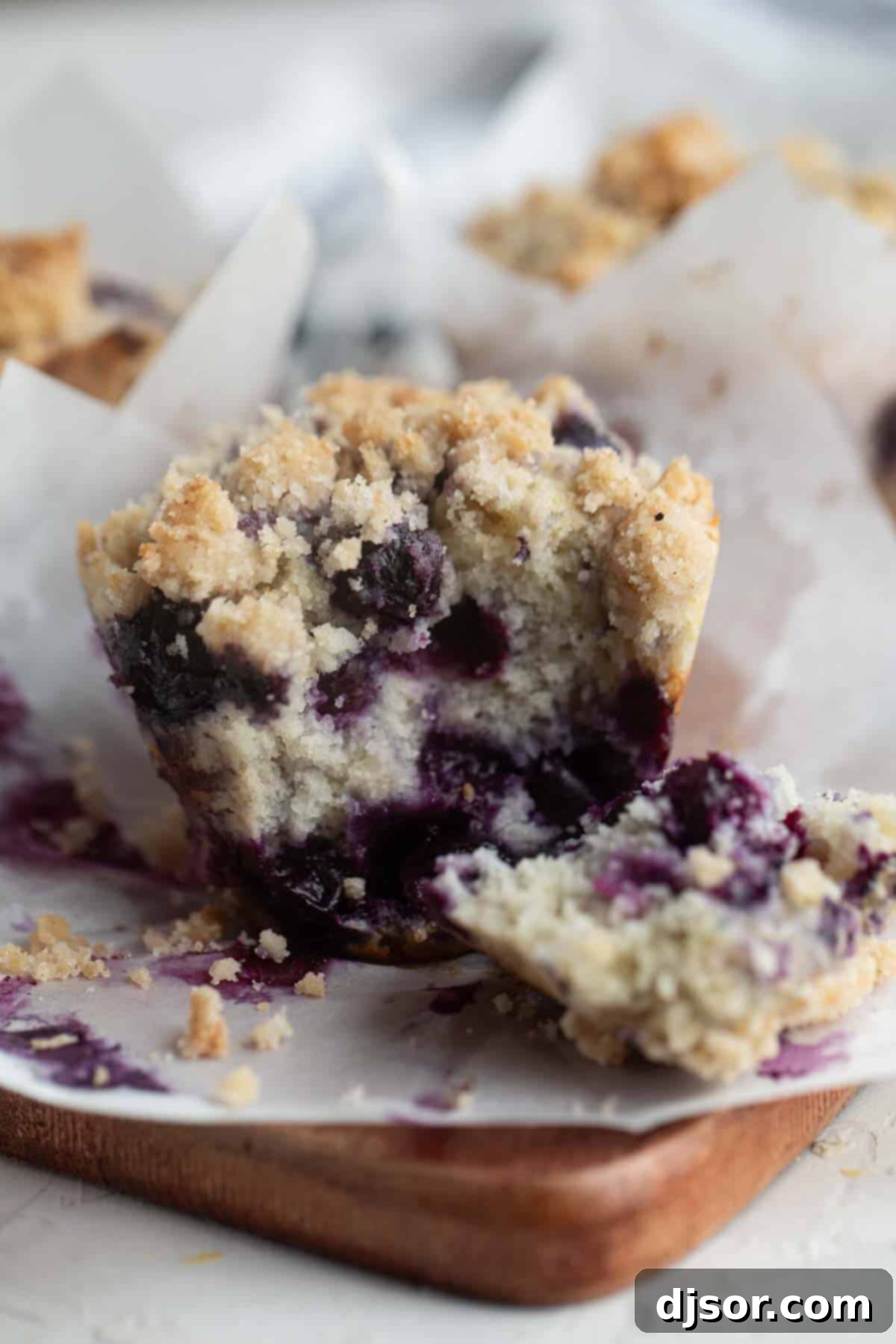 A blueberry muffin torn in half to reveal its moist interior and abundance of blueberries.