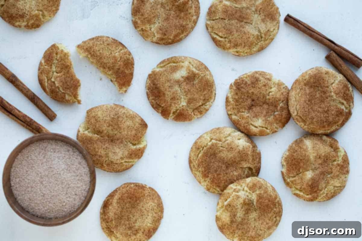 Perfectly soft, this is the best Snickerdoodle Recipe! This popular cinnamon sugar cookie recipe holds up for several days and requires no chilling time. You can have a batch on the table in no time! Freshly baked Snickerdoodle cookies with cinnamon sticks and a bowl of cinnamon sugar, ready to be enjoyed.
