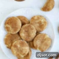 The Best Snickerdoodle Cookie Recipe 2 An overhead shot of a plate brimming with golden-brown Snickerdoodle cookies, coated in cinnamon sugar.