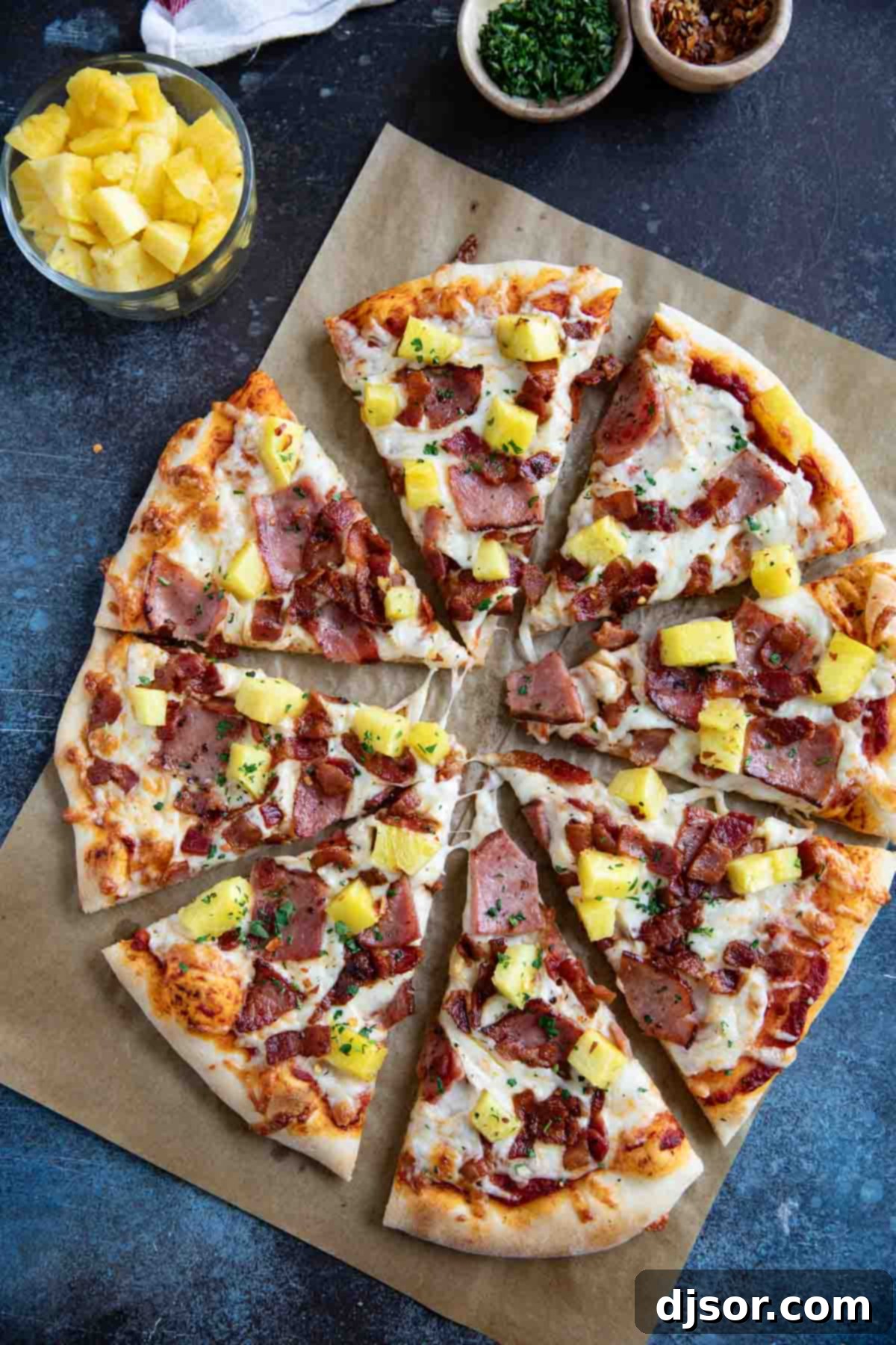 A freshly baked Hawaiian Pizza, perfectly round and golden, expertly cut into eight generous slices, showcasing its abundant toppings of ham, bacon, pineapple, and melted cheese.