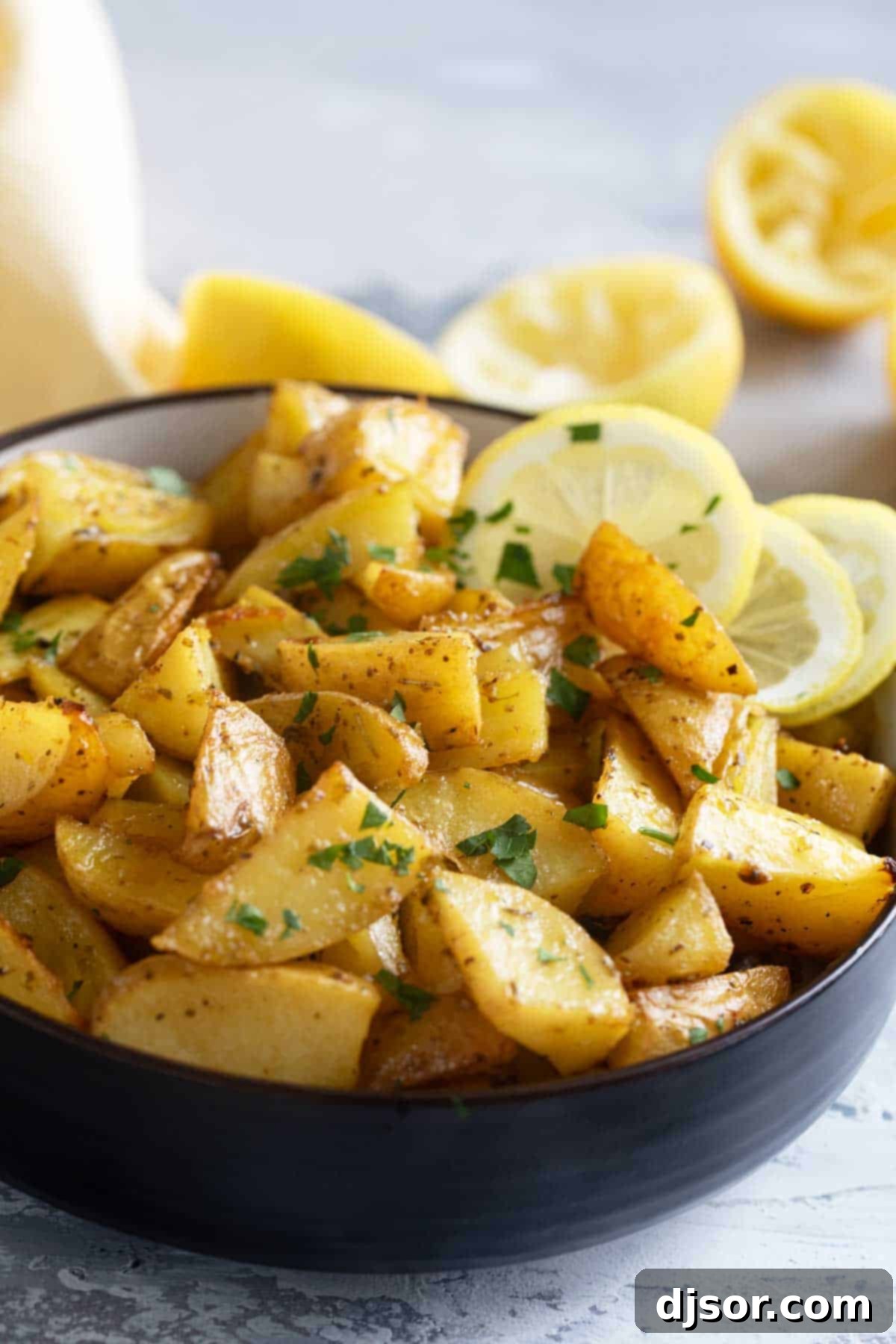 A rustic bowl overflowing with golden-brown Greek Lemon Potatoes, garnished with fresh lemon slices and a sprinkle of herbs, inviting you to taste.