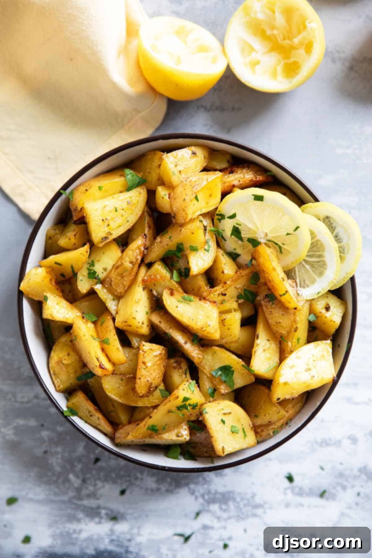 Zesty Greek Lemon Potatoes 6 Close-up of golden brown Greek Lemon Potatoes cut into wedges in a white bowl.
