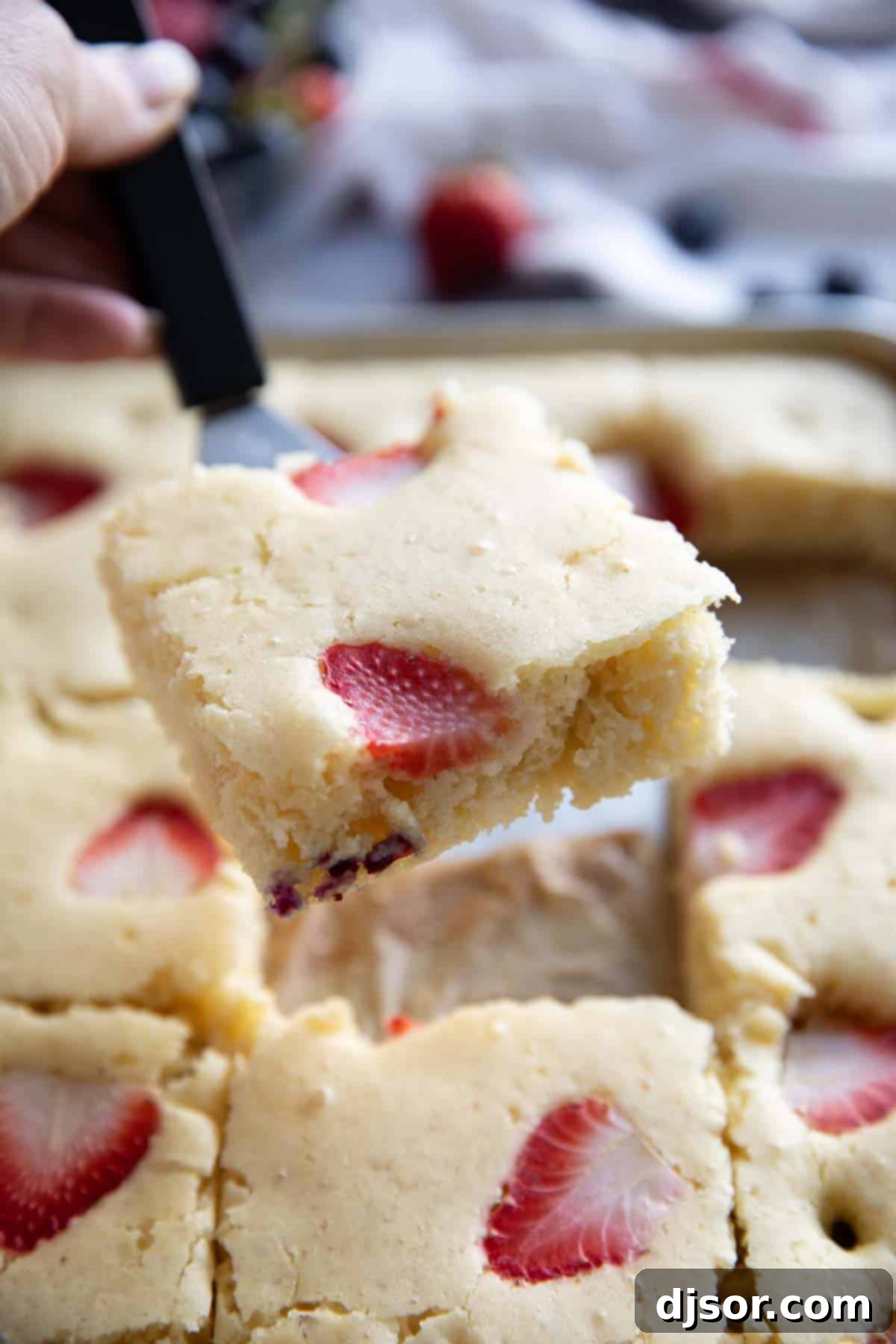 Slice of sheet pan pancakes being taken from pan with a small spatula.