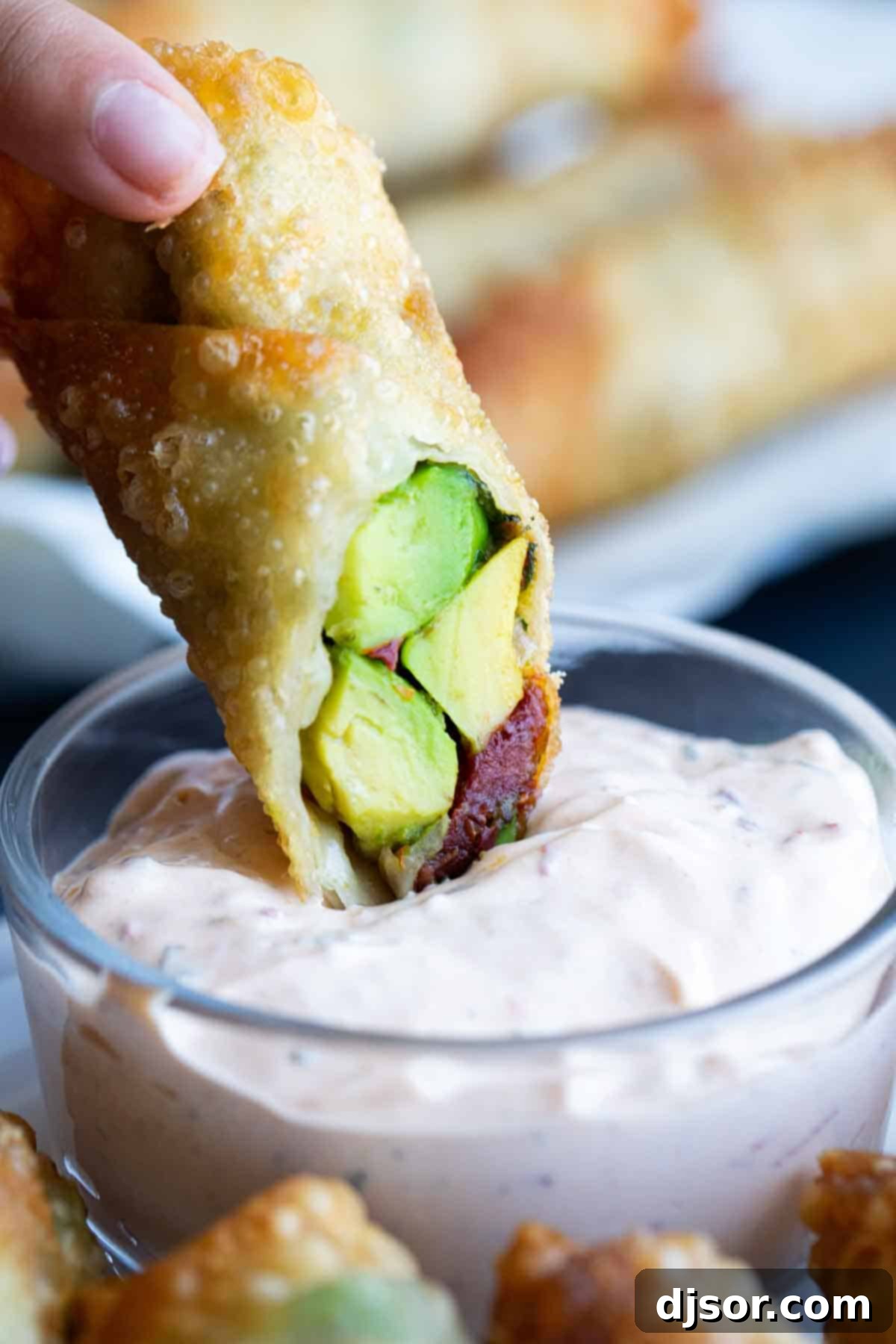 Dipping a crispy avocado egg roll into creamy Chipotle Ranch Sauce