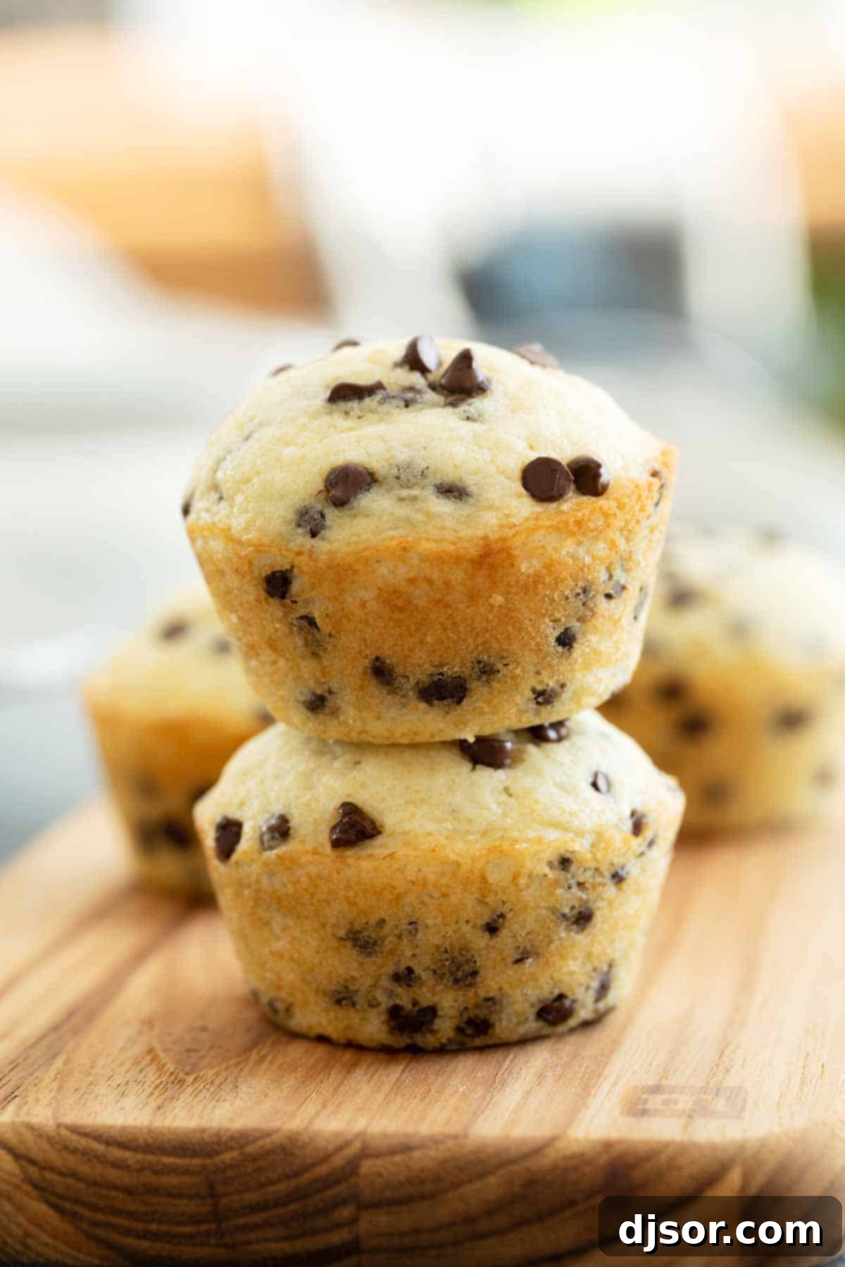 Stack of freshly baked chocolate chip muffins, showcasing their golden tops and tender interior on a wire cooling rack.