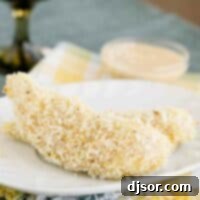 Coconut Chicken Tenders on a plate with creamy mango chutney in the back.