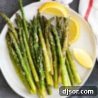 An overhead view of a white plate filled with beautifully roasted asparagus, garnished with fresh lemon wedges, ready to be served as a healthy side.
