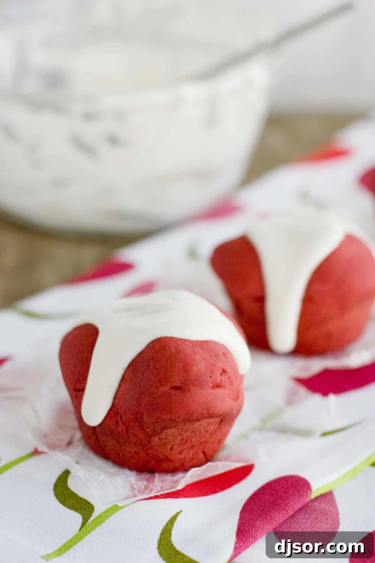 Two red velvet rolls topped with cream cheese glaze, perfectly arranged on a plate.