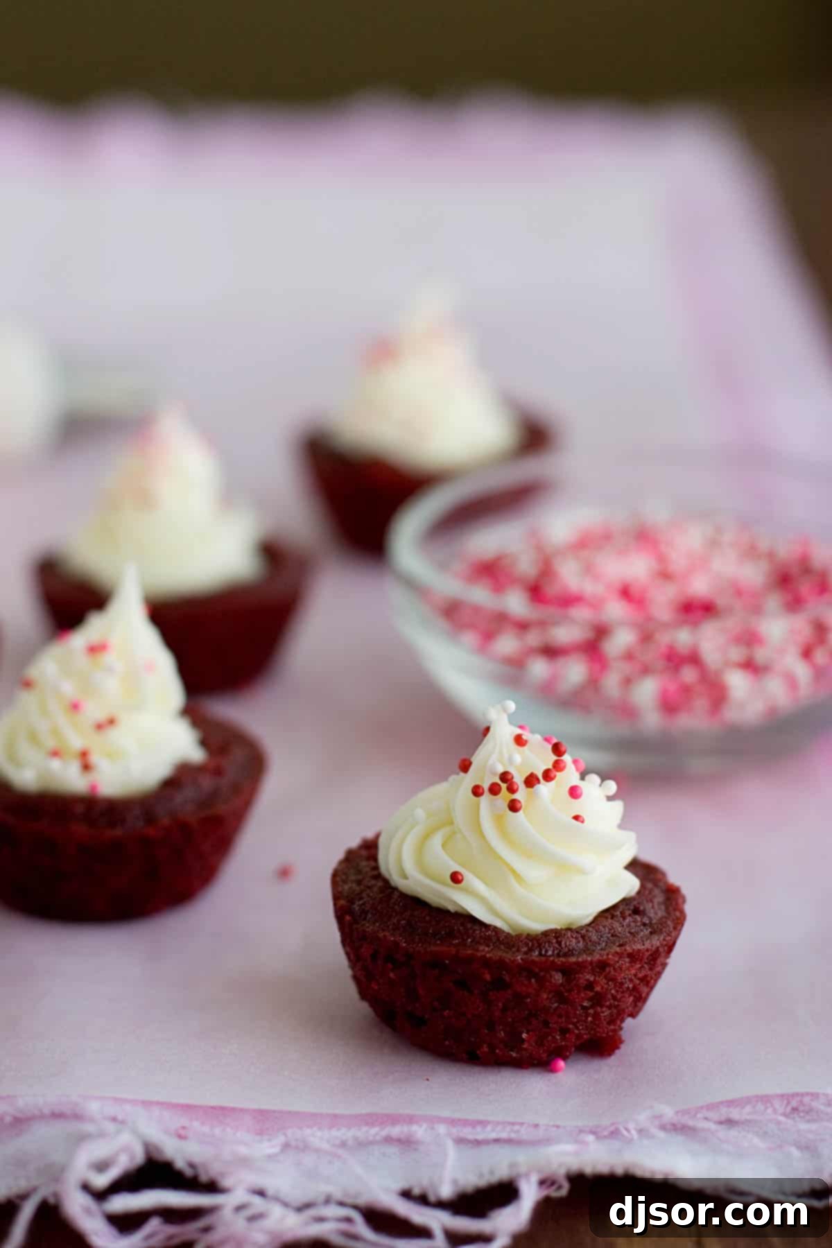 Red velvet brownie cups filled with cream cheese and topped with sprinkles.