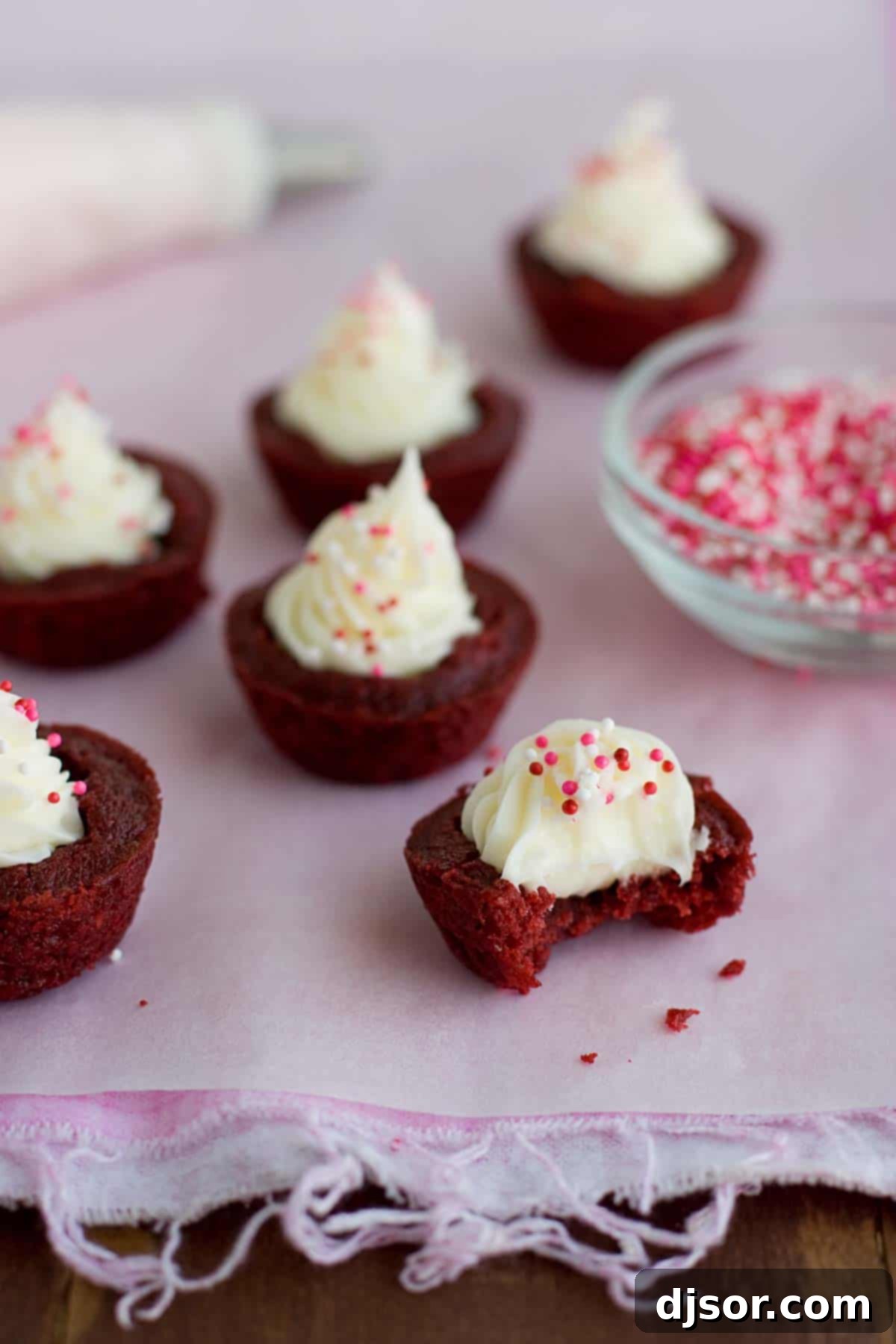 Delicious Red Velvet Brownie Cup, partially eaten A close-up of a Red Velvet Brownie Cup with a bite taken, revealing the rich brownie and creamy filling.