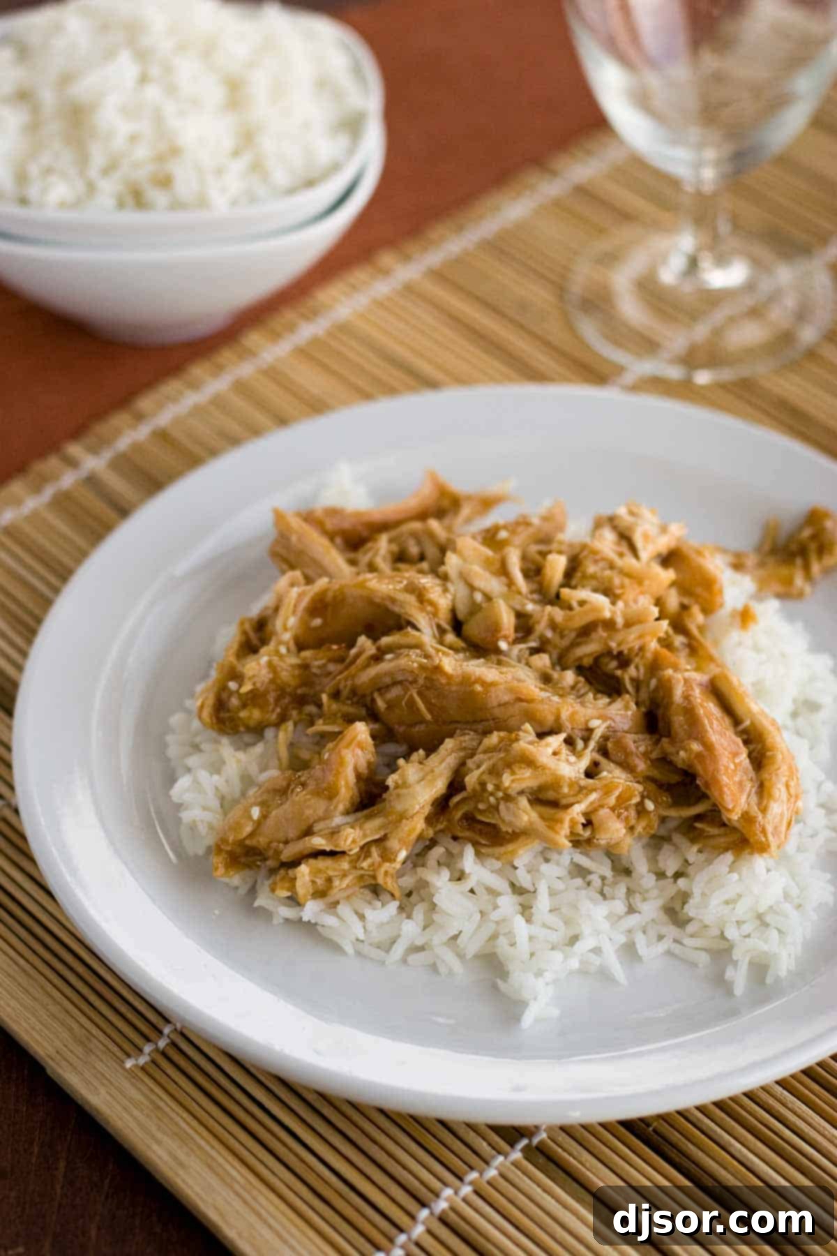 Golden Glazed Slow Cooker Teriyaki Chicken 2 Plate with slow cooker chicken teriyaki over white rice, garnished with sesame seeds.