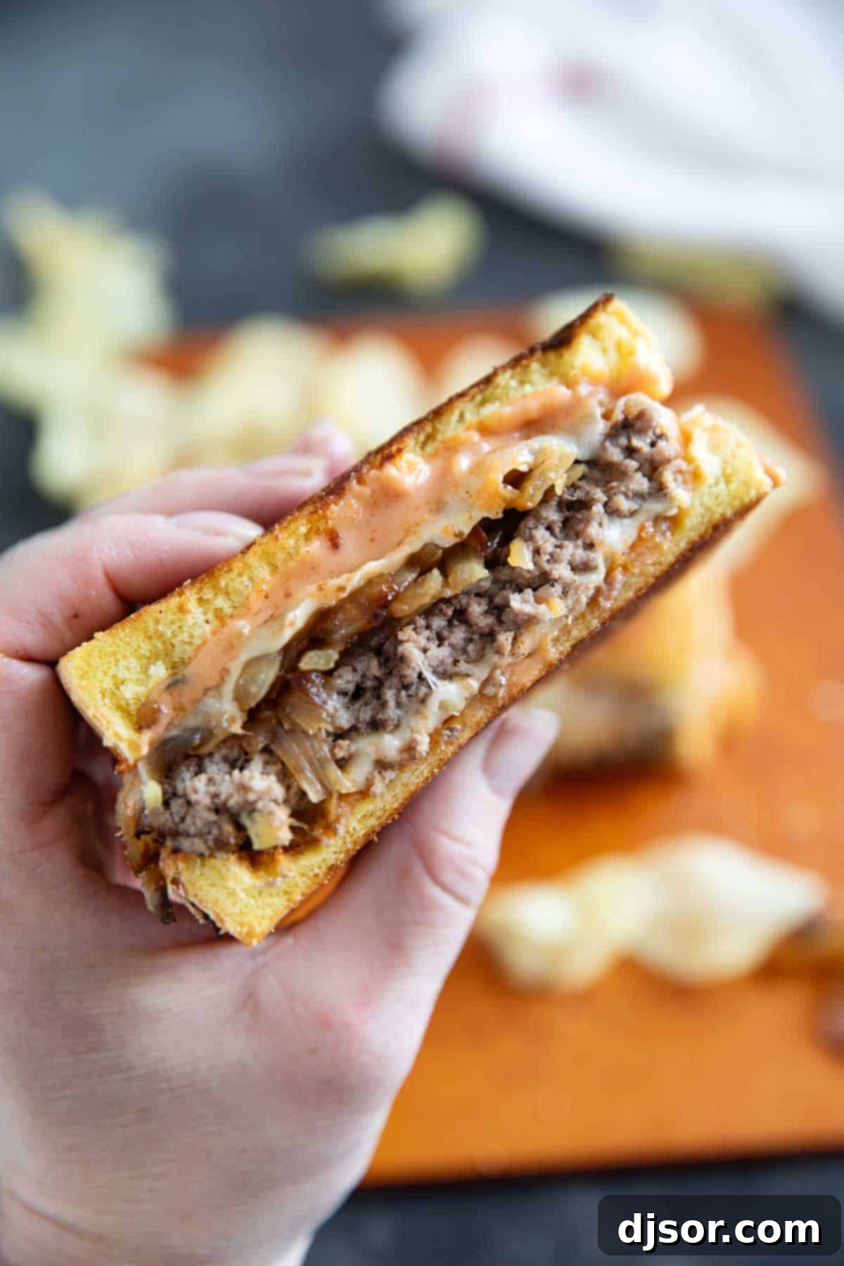 Classic Patty Melt 8 A hand holding half of a Patty Melt, showing the layers of ingredients.