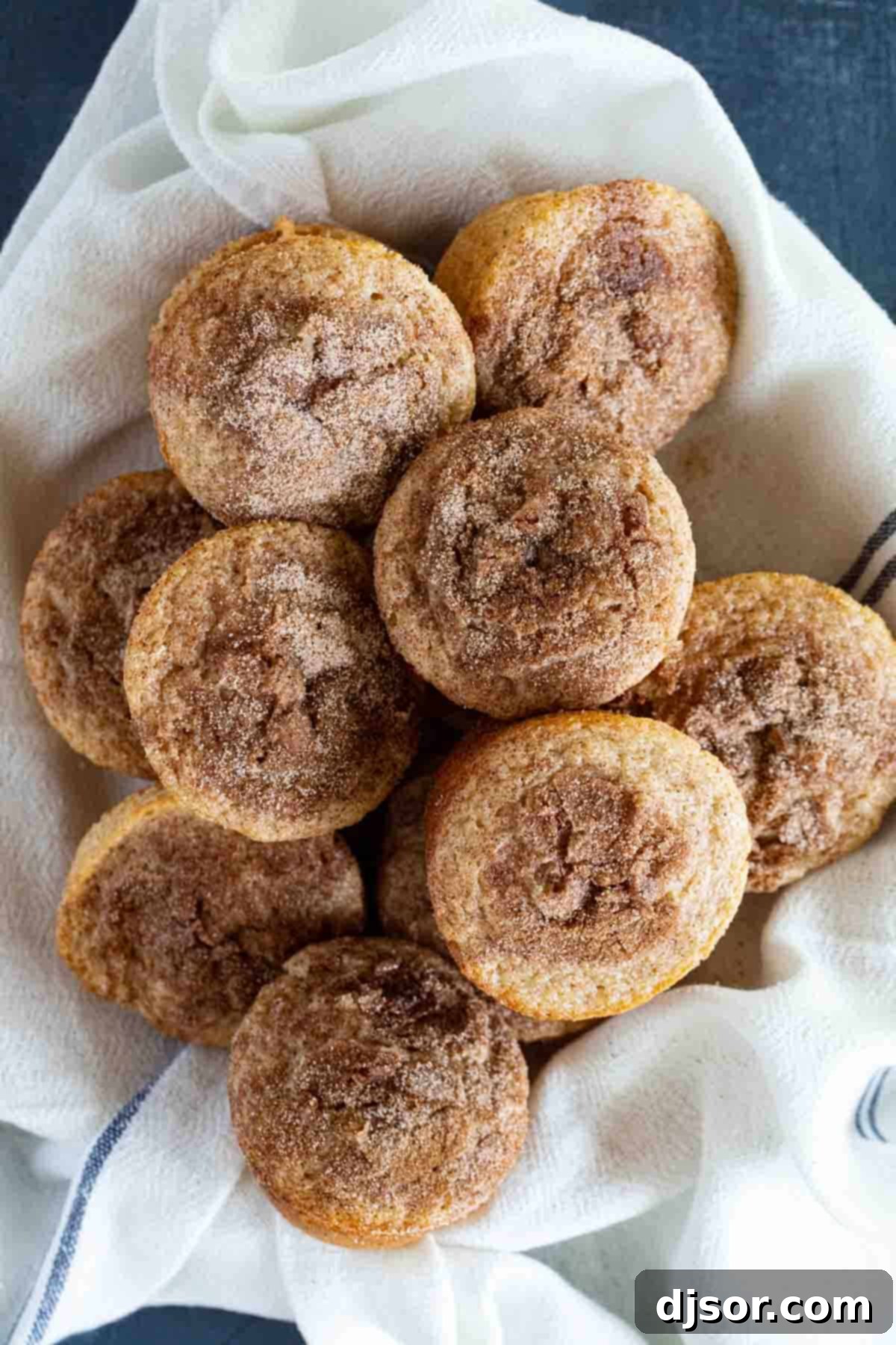 A large bowl generously filled with freshly baked Cinnamon Muffins, showcasing their perfect domed tops and inviting cinnamon-sugar crust.