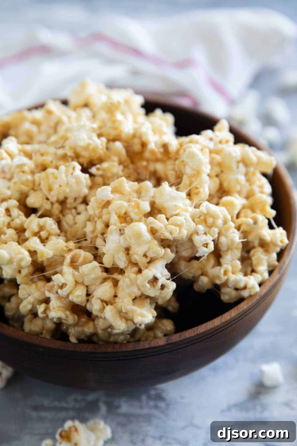 Gourmet Caramel Marshmallow Popcorn Clusters 2 Wooden bowl filled with caramel marshmallow popcorn, showcasing its gooey texture.