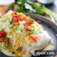 Smothered Burritos with ground beef and refried beans, covered in green Chile sauce, cheese, tomatoes, and lettuce.