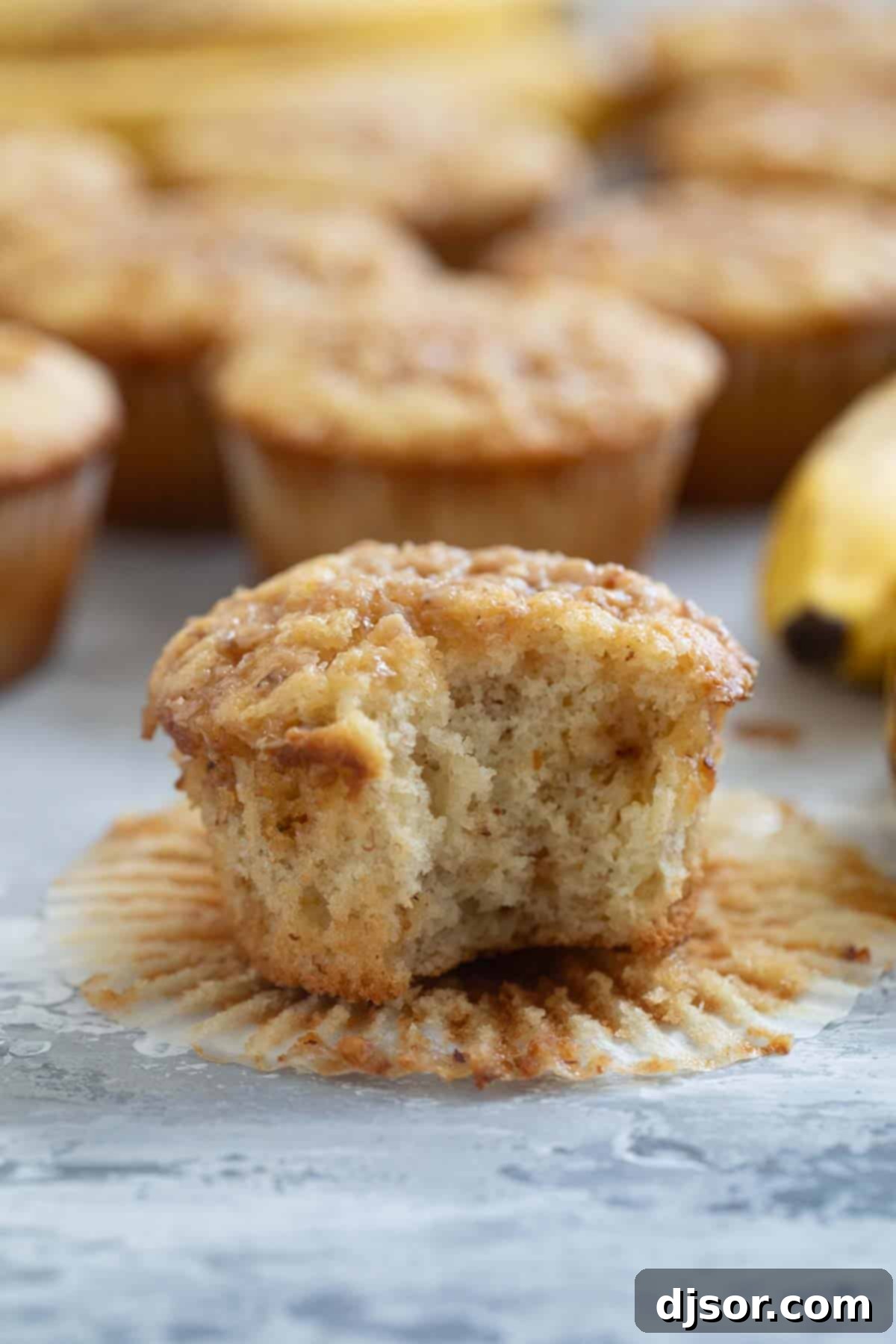Banana Toffee Treat Muffins 8 A delicious Banana Toffee Muffin with a bite taken out, revealing its moist interior and scattered toffee pieces.