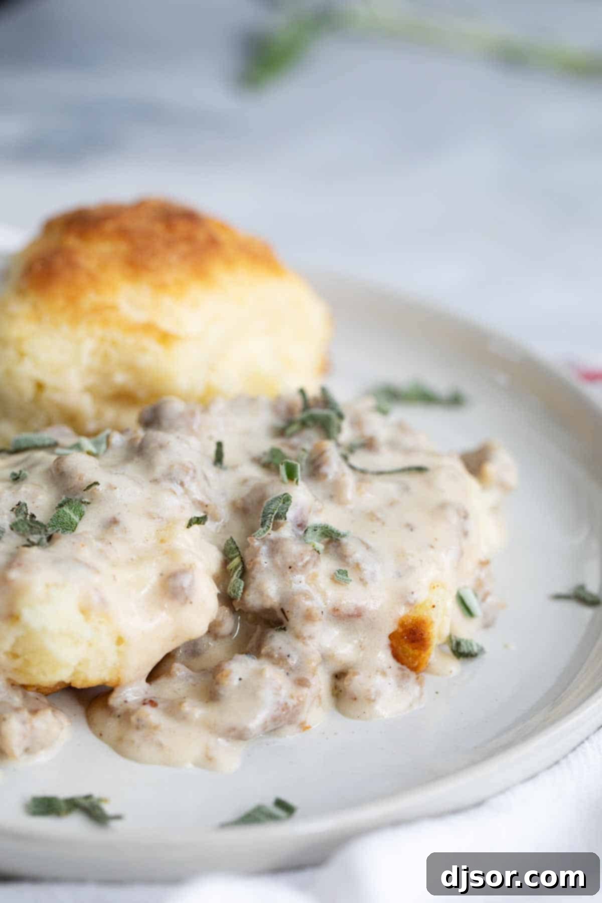 Beautifully plated homemade fluffy biscuits generously topped with savory sausage gravy, ready to be enjoyed.