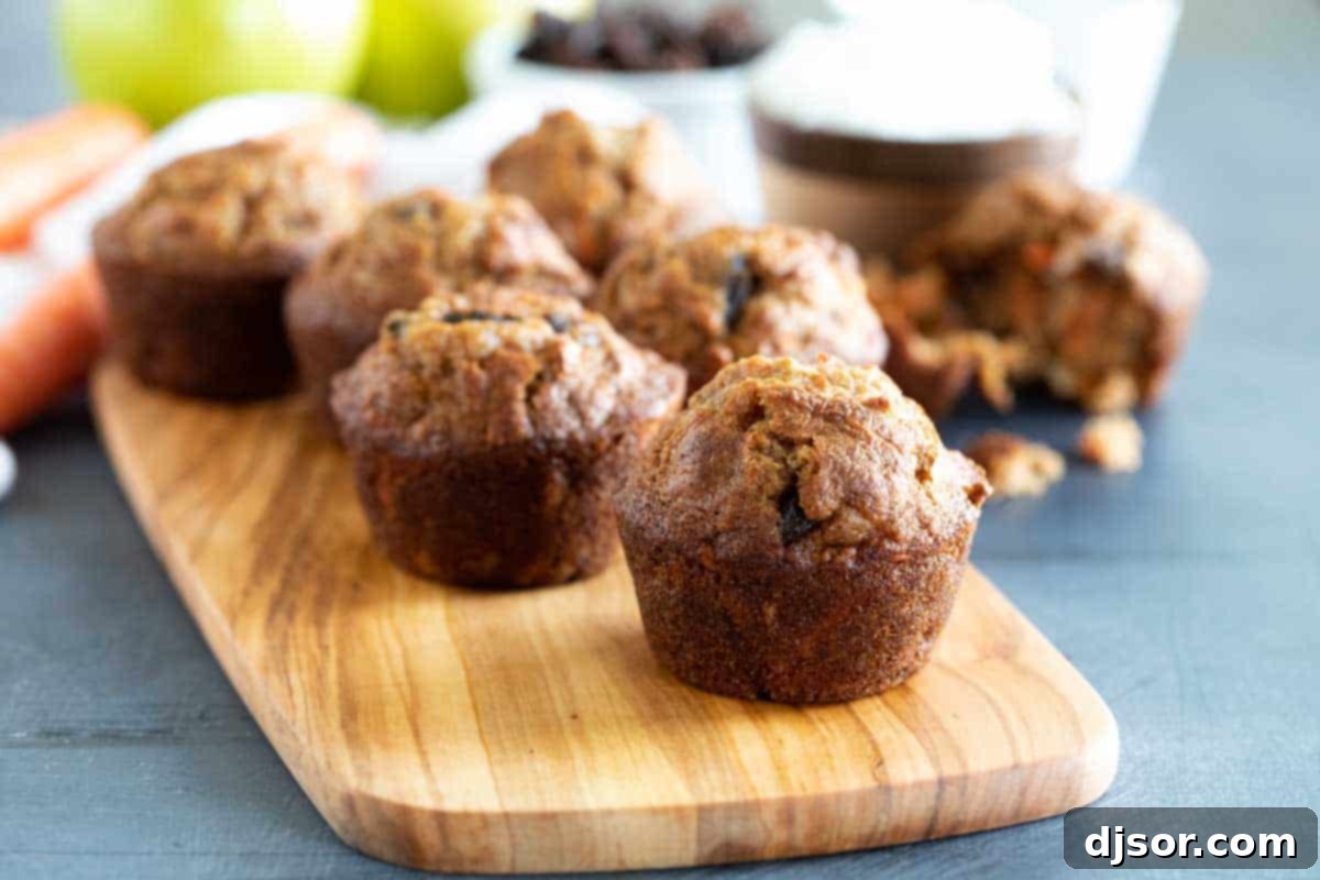 Wholesome Morning Glory Muffins: Carrots, Apples, Raisins, Coconut, Nuts Freshly baked Morning Glory Muffins arranged on a rustic wooden board, ready for breakfast.
