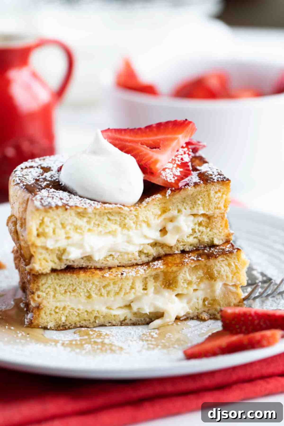 Stuffed French Toast cut and stacked topped with strawberries, whipped cream, and powdered sugar