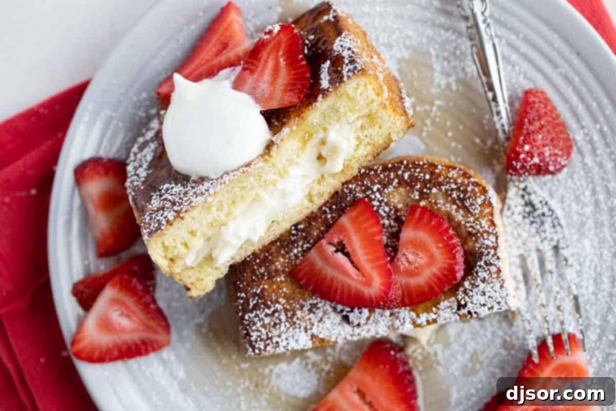 Stuffed French Toast cut in half showing filling, topped with strawberries