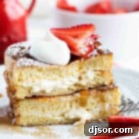 Stuffed French Toast cut and stacked topped with strawberries, whipped cream, and powdered sugar