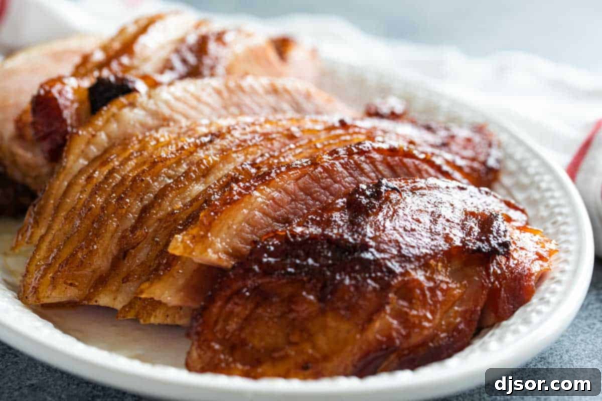 A beautifully golden-brown Honey Glazed Ham on a large platter, garnished and ready for serving at a holiday feast.